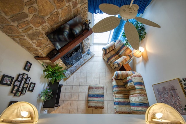 tiled living area featuring a stone fireplace