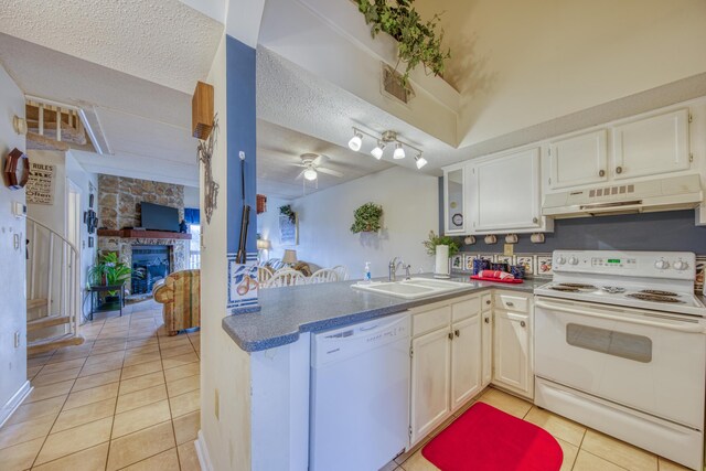 kitchen featuring white appliances, a ceiling fan, under cabinet range hood, a fireplace, and a sink