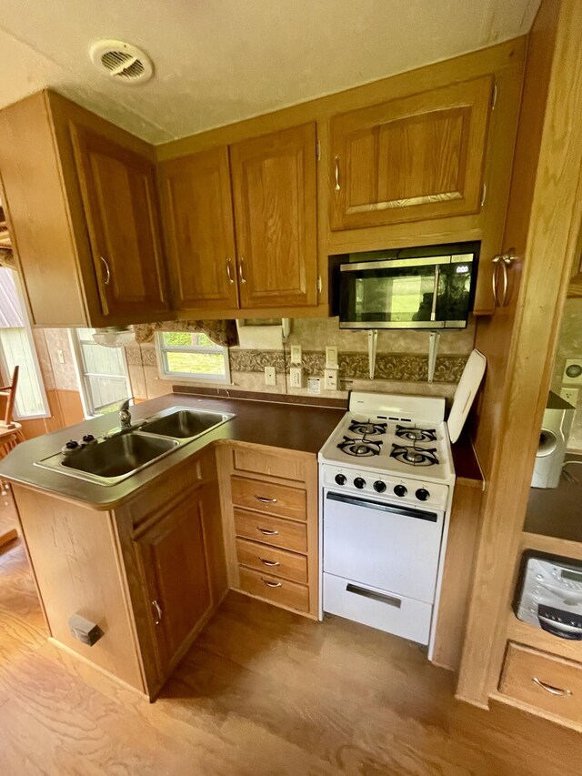 4124 Big Creek Rd, Hartford, TN 37753 - kitchen with white range with gas cooktop, stainless steel microwave, a sink, brown cabinets, and dark wood-style floors