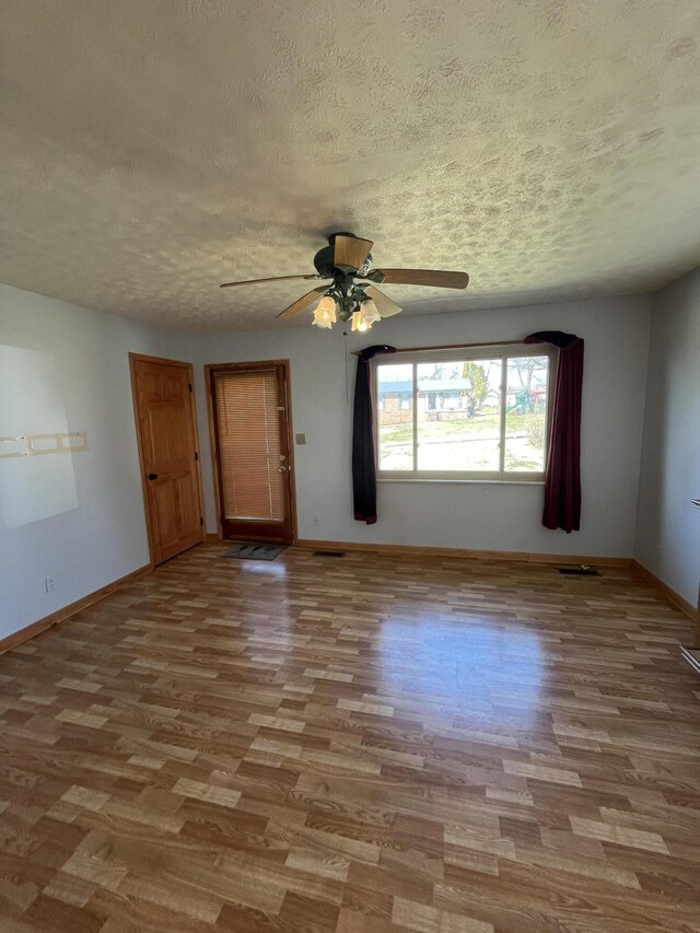 spare room featuring a textured ceiling, wood finished floors, a ceiling fan, and baseboards