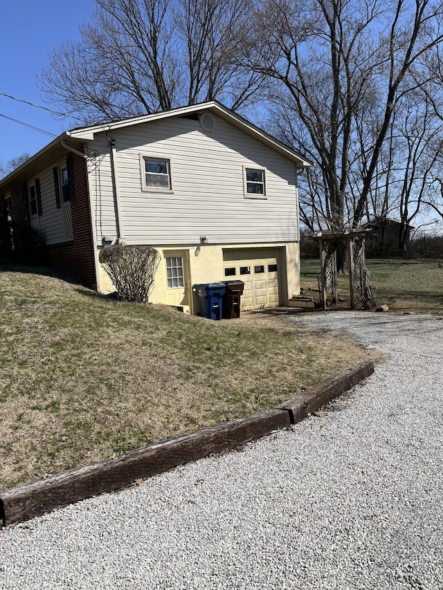 view of property exterior with an attached garage, a lawn, and gravel driveway