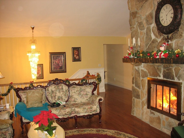 living area with a notable chandelier, wood finished floors, and a stone fireplace