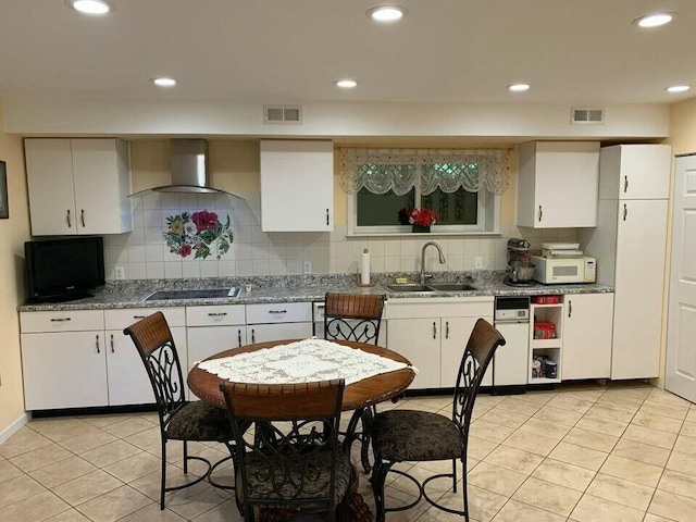 kitchen featuring visible vents, a sink, wall chimney range hood, and white microwave