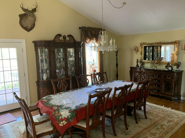 dining space with lofted ceiling, a notable chandelier, and wood finished floors