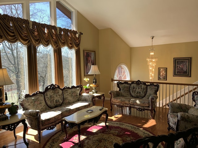 living room with high vaulted ceiling, an inviting chandelier, and wood finished floors