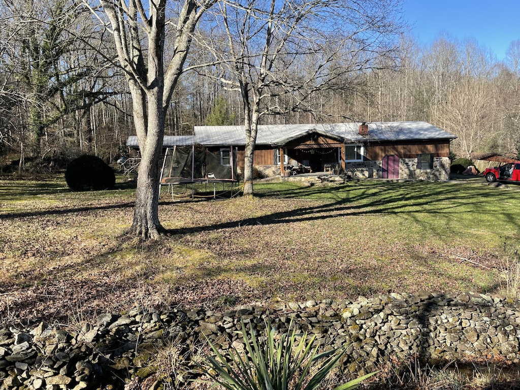 view of front of home with a trampoline and a front lawn