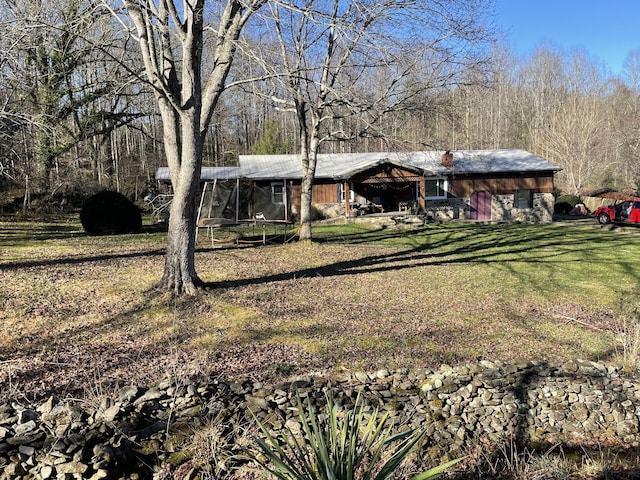 view of front of home with a trampoline and a front lawn