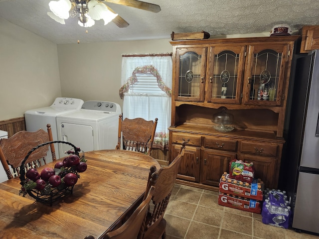 dining space featuring washing machine and dryer, ceiling fan, wood walls, and a textured ceiling