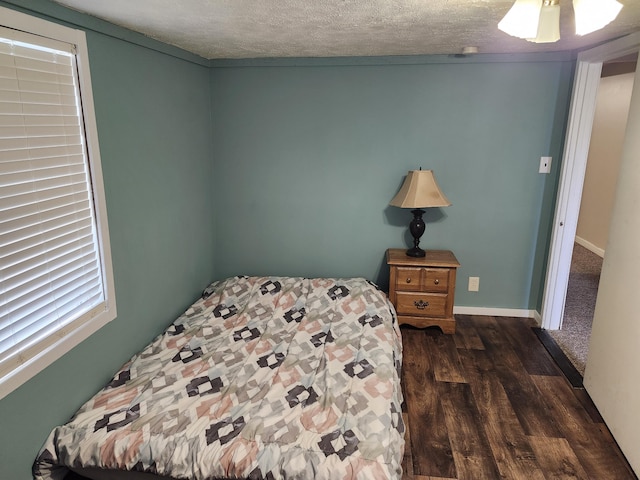 bedroom featuring ceiling fan, dark hardwood / wood-style floors, and a textured ceiling