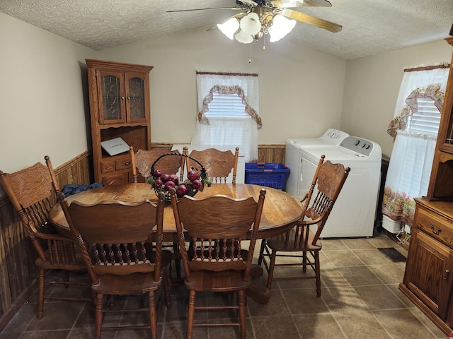 dining area featuring ceiling fan, separate washer and dryer, wood walls, lofted ceiling, and a textured ceiling