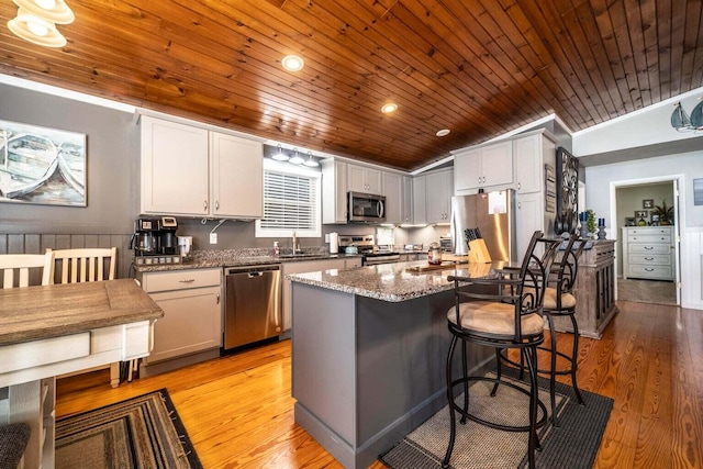 1662 Canal Ln, Dandridge, TN 37725 - kitchen with stainless steel appliances, wood ceiling, light wood-style flooring, a kitchen breakfast bar, and stone counters