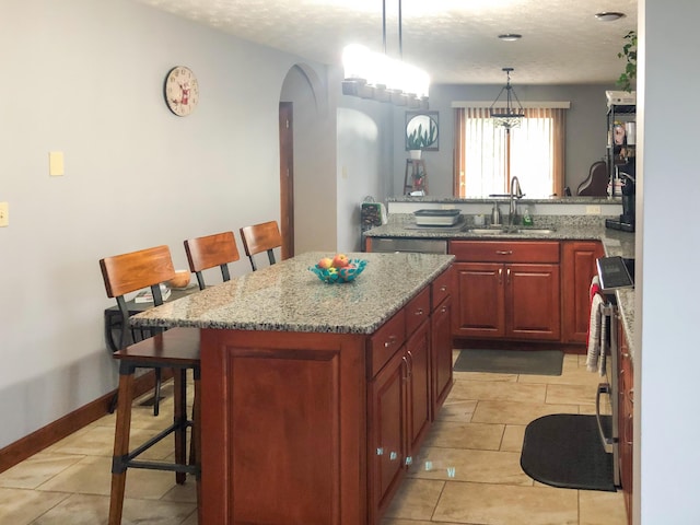 4815 Stapleton Rd, Morristown, TN 37813 - kitchen featuring a breakfast bar, a kitchen island, light tile patterned floors, arched walkways, and light stone countertops
