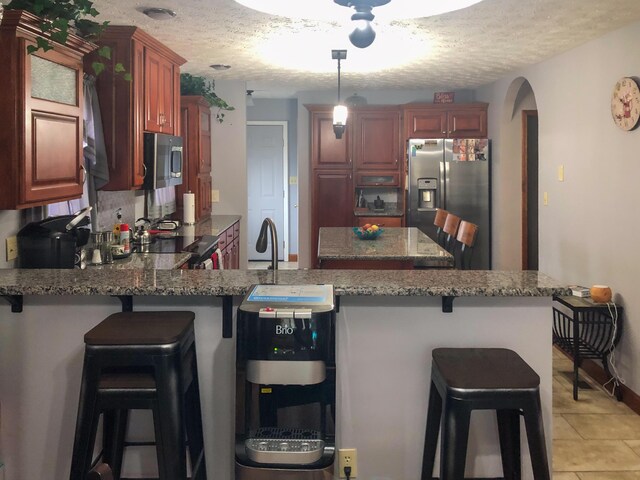 4815 Stapleton Rd, Morristown, TN 37813 - kitchen with appliances with stainless steel finishes, a peninsula, a textured ceiling, arched walkways, and light stone counters