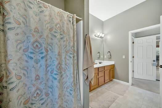 bathroom with a shower with curtain, tile patterned floors, baseboards, and vanity