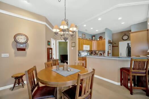 dining room featuring vaulted ceiling, baseboards, a notable chandelier, and recessed lighting