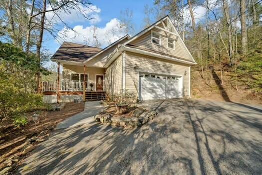 view of side of home featuring driveway, covered porch, and an attached garage