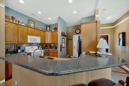 kitchen with a breakfast bar area, tasteful backsplash, stove, white microwave, and a peninsula