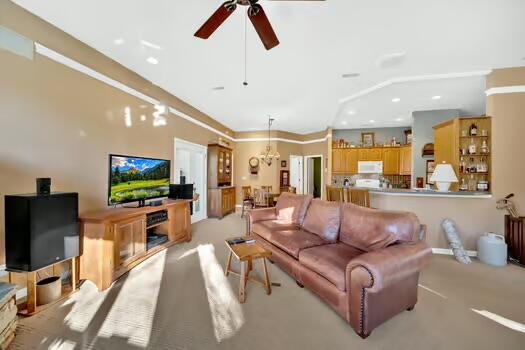 living area with ceiling fan with notable chandelier, recessed lighting, and light colored carpet