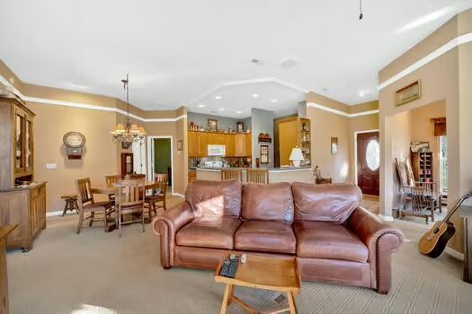 living room featuring an inviting chandelier, recessed lighting, and light colored carpet