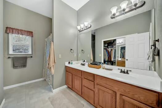 bathroom with double vanity, baseboards, and a sink