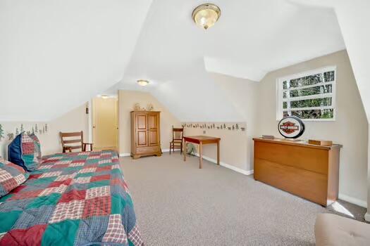 carpeted bedroom with vaulted ceiling and baseboards