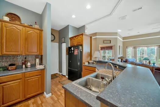 kitchen with visible vents, decorative backsplash, freestanding refrigerator, a sink, and light wood-type flooring