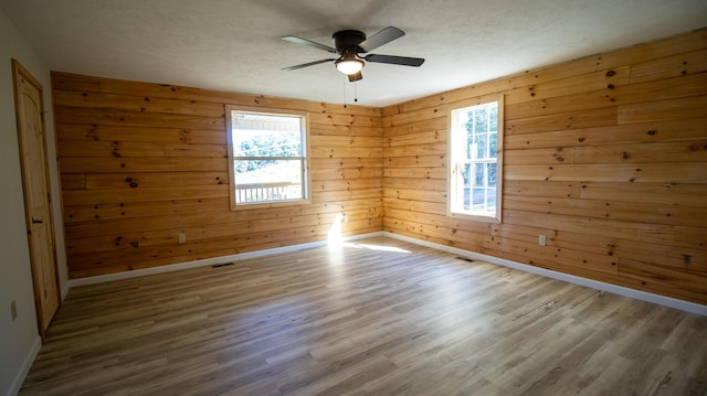 empty room with wood walls, ceiling fan, and wood-type flooring