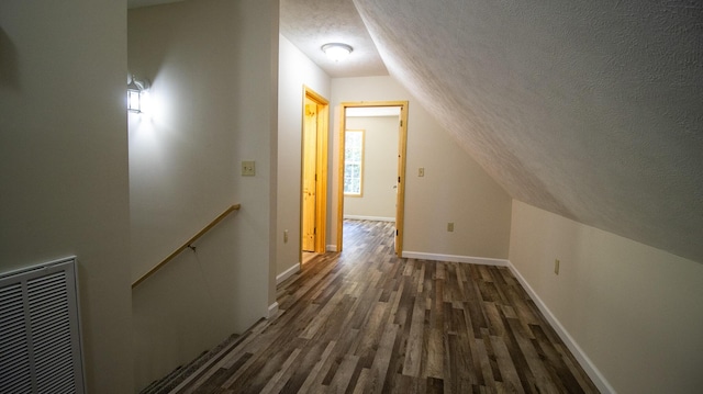 hall featuring dark hardwood / wood-style flooring, a textured ceiling, and vaulted ceiling