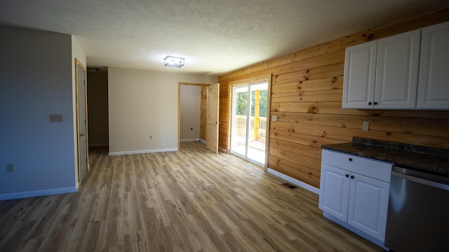 interior space with white cabinets, dishwasher, light wood-type flooring, and wooden walls