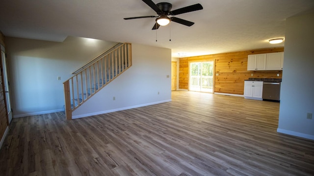 unfurnished living room with wood walls, dark hardwood / wood-style flooring, and ceiling fan