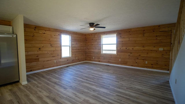 empty room with hardwood / wood-style flooring, ceiling fan, and wooden walls