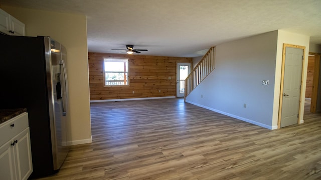 interior space with ceiling fan, wooden walls, and light hardwood / wood-style flooring