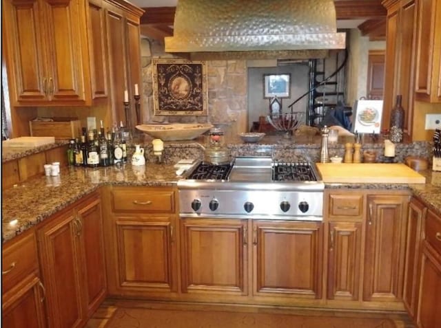 kitchen featuring stainless steel gas stovetop, light stone counters, and wall chimney range hood