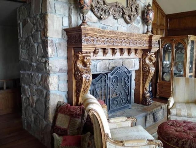 sitting room with hardwood / wood-style floors, a stone fireplace, and wooden walls