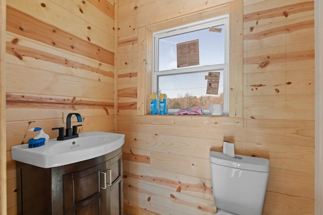 bathroom with vanity, toilet, and wooden walls