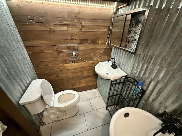 bathroom with toilet, vanity, tile patterned floors, and wood walls