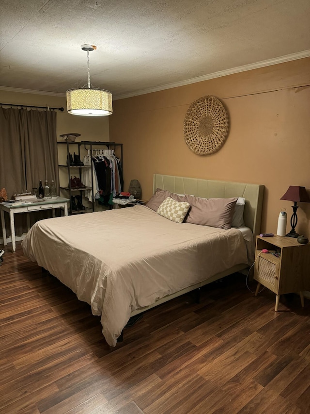 bedroom with ornamental molding, a textured ceiling, and dark wood-type flooring