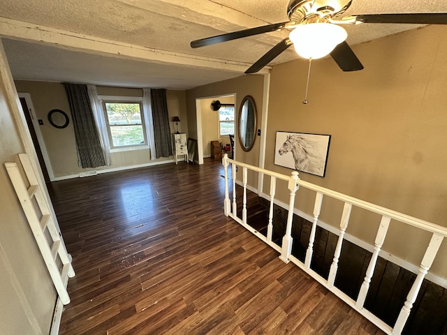 interior space with beamed ceiling, a textured ceiling, and dark hardwood / wood-style floors