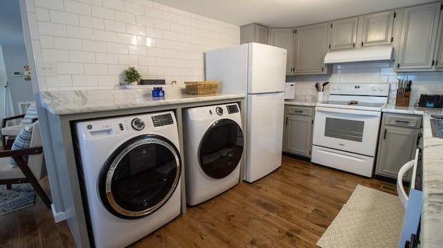 kitchen featuring decorative backsplash, under cabinet range hood, white appliances, and independent washer and dryer