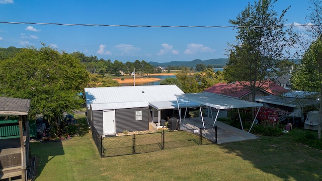 back of property featuring a gate, a fenced backyard, a yard, a water view, and metal roof