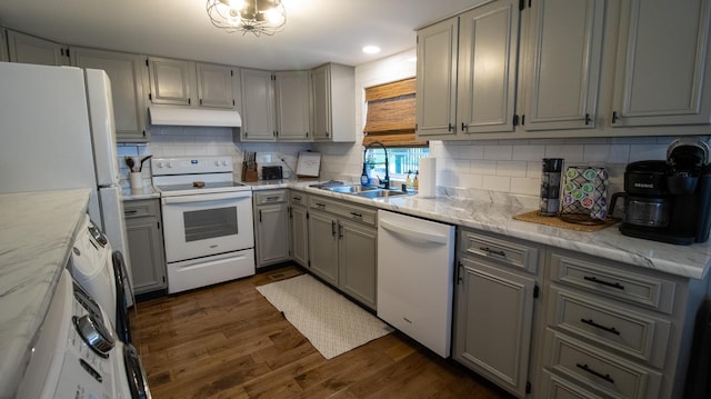 kitchen with tasteful backsplash, a sink, under cabinet range hood, white appliances, and dark wood-style flooring