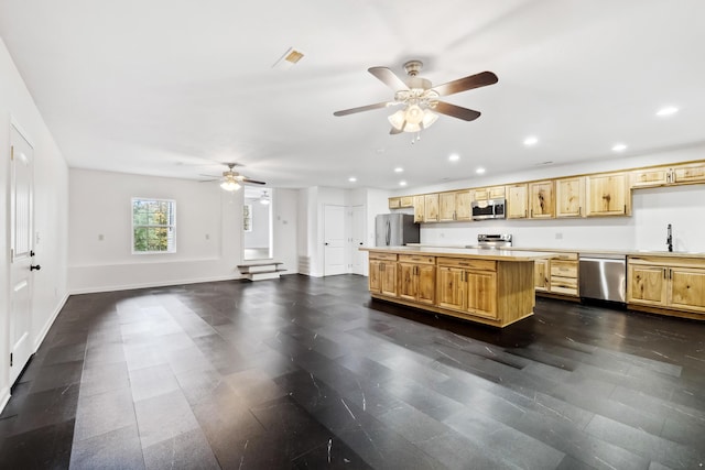 kitchen with appliances with stainless steel finishes, ceiling fan, sink, light brown cabinets, and a kitchen island