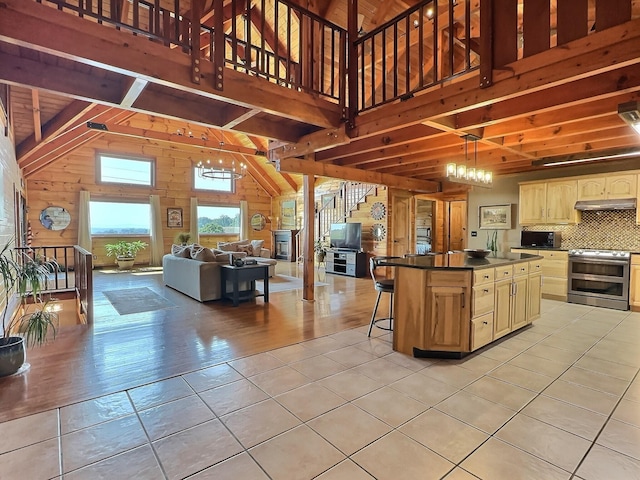 kitchen featuring tasteful backsplash, a chandelier, stainless steel electric range, a kitchen bar, and a kitchen island