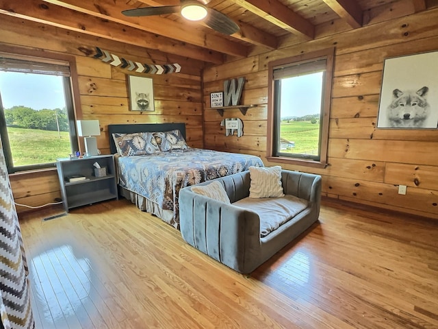 bedroom featuring wood walls, light hardwood / wood-style flooring, beamed ceiling, and wood ceiling