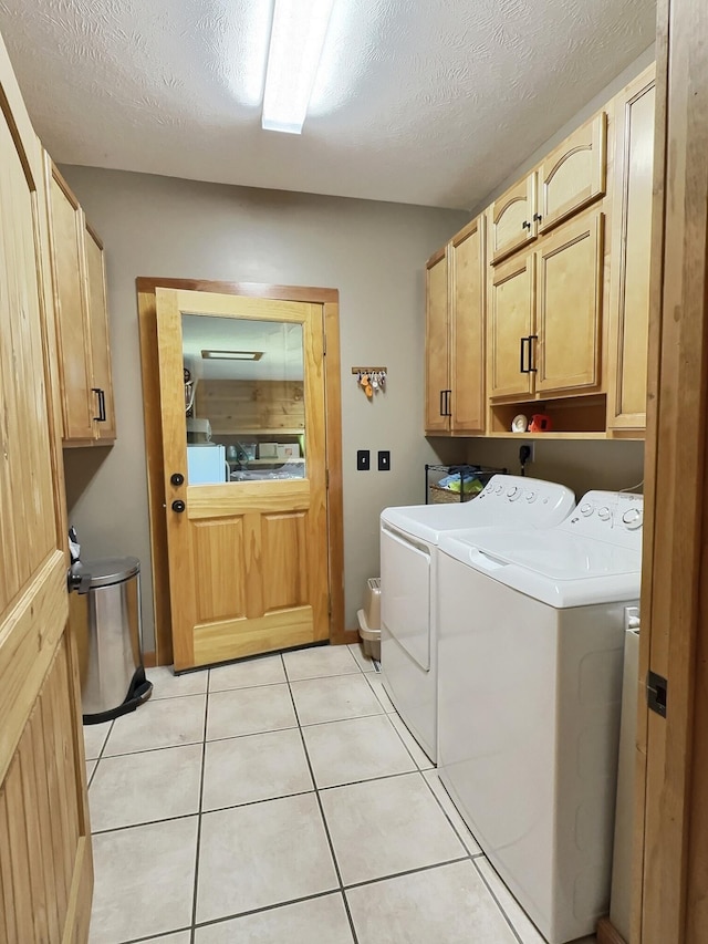 laundry area with light tile patterned floors, cabinets, a textured ceiling, and independent washer and dryer