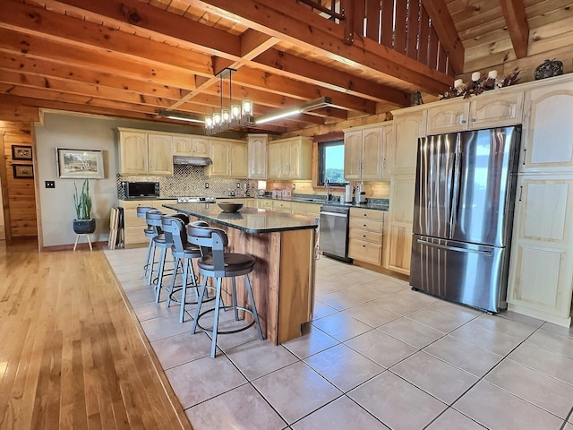 kitchen with light tile patterned flooring, sink, a breakfast bar area, a kitchen island, and stainless steel appliances