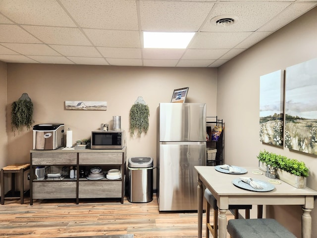 kitchen with a paneled ceiling, light wood-type flooring, and appliances with stainless steel finishes