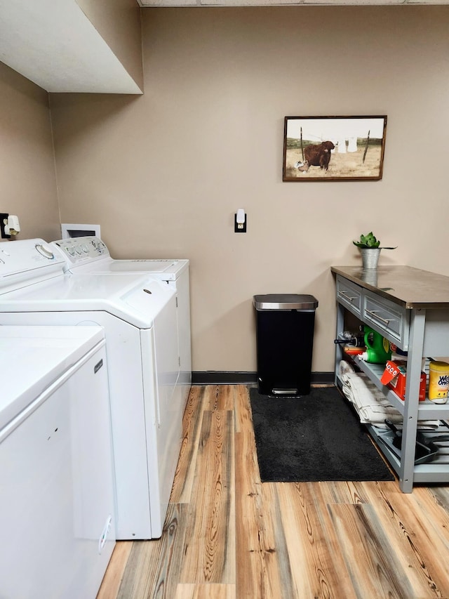 clothes washing area with washing machine and dryer and light hardwood / wood-style flooring