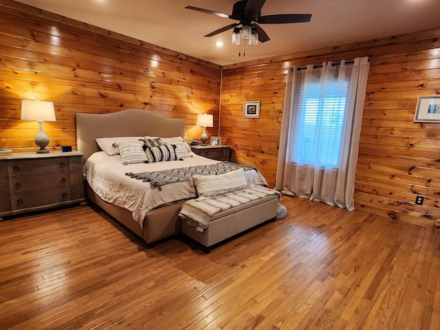 bedroom featuring wood walls, ceiling fan, and light hardwood / wood-style floors