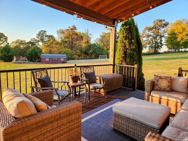 wooden terrace featuring a yard, a storage unit, an outdoor hangout area, and a trampoline